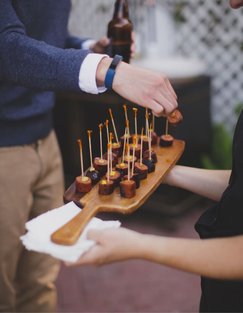 Servers presenting canapés on a wooden board